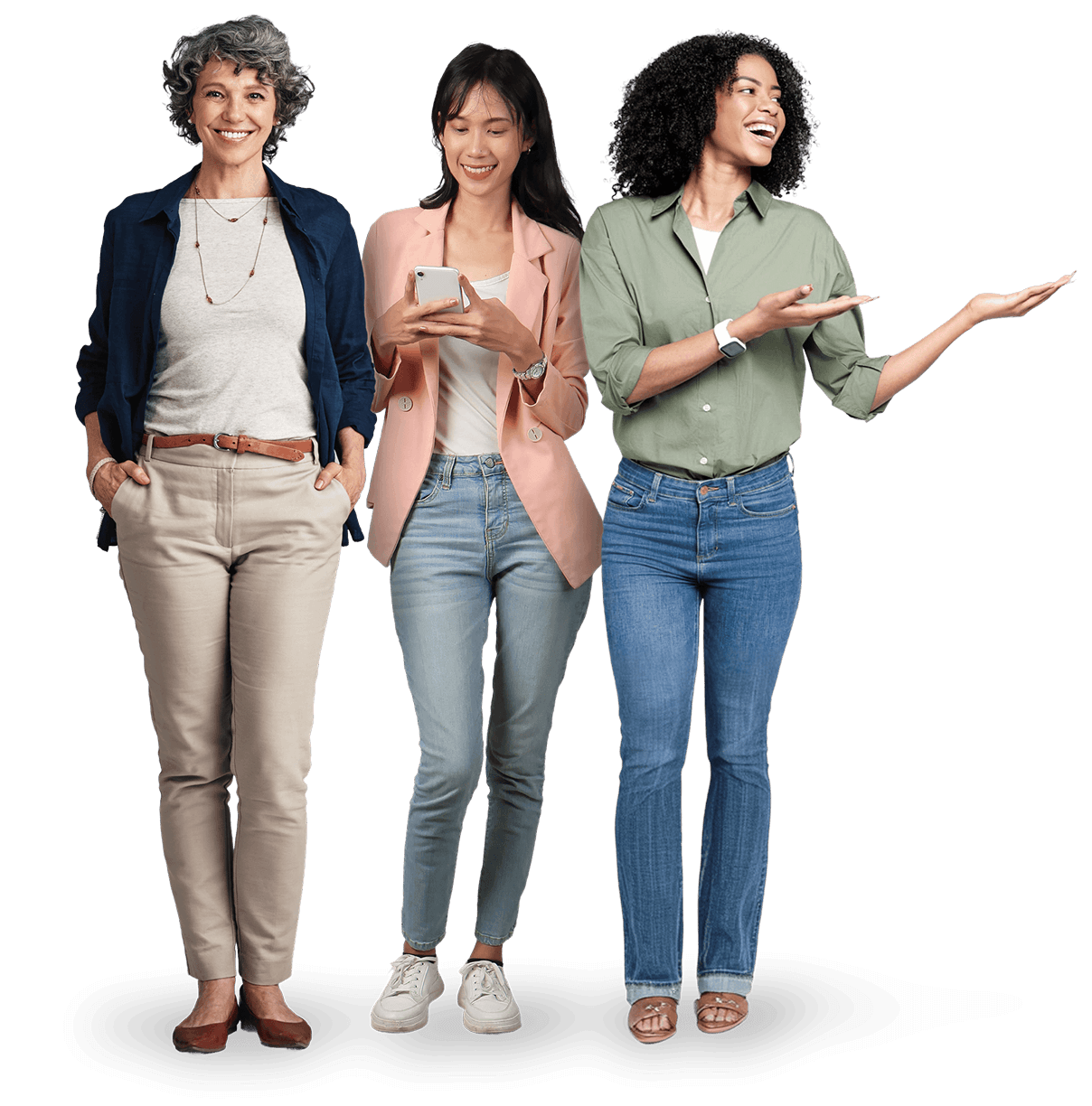 Trois femmes se tiennent ensemble. Une femme plus âgée sourit, les mains dans les poches, une femme plus jeune au milieu tient un téléphone et regarde vers le bas, et la troisième femme fait un geste sur le côté tout en souriant. Toutes sont habillées de manière décontractée.